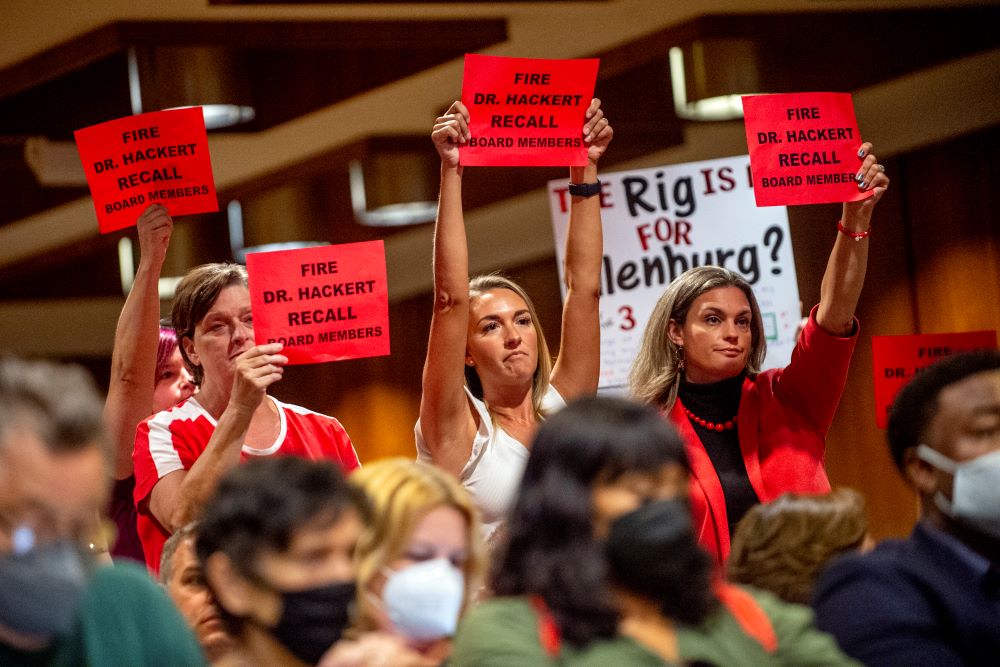 Parents and residents stand to oppose the county's K-6 school mask mandate after public comment finished as more than 100 people pack the Harris Auditorium at a Genesee County Board of Commissioners meeting Aug. 30, 2021.