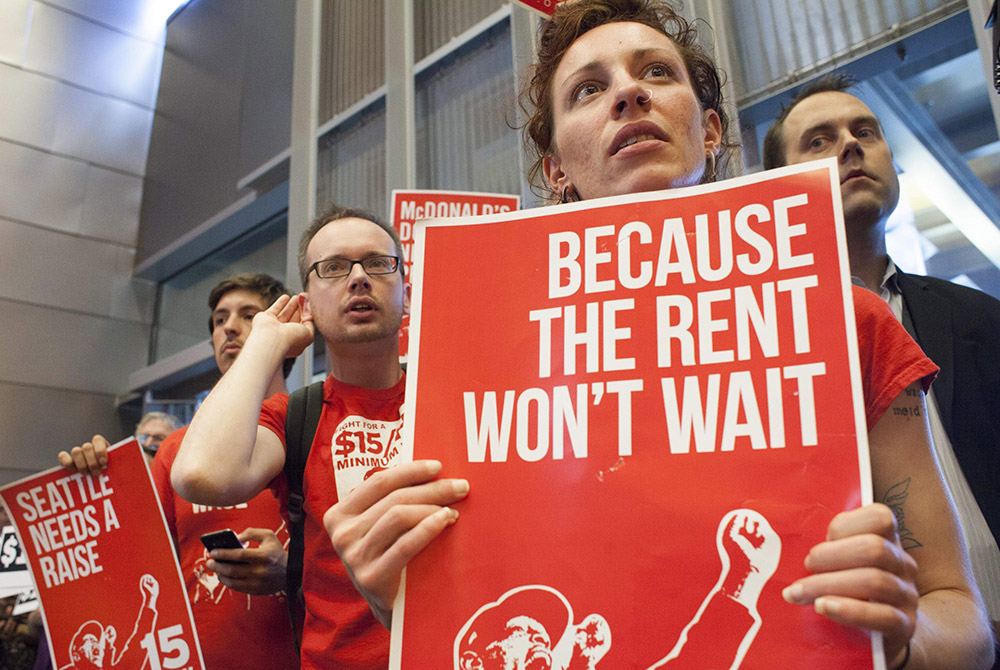 Labor activists hold signs during a Seattle City Council meeting in which the council voted on raising the minimum wage to $15 per hour, June 2, 2014, in Seattle. (CNS/David Ryder, Reuters)