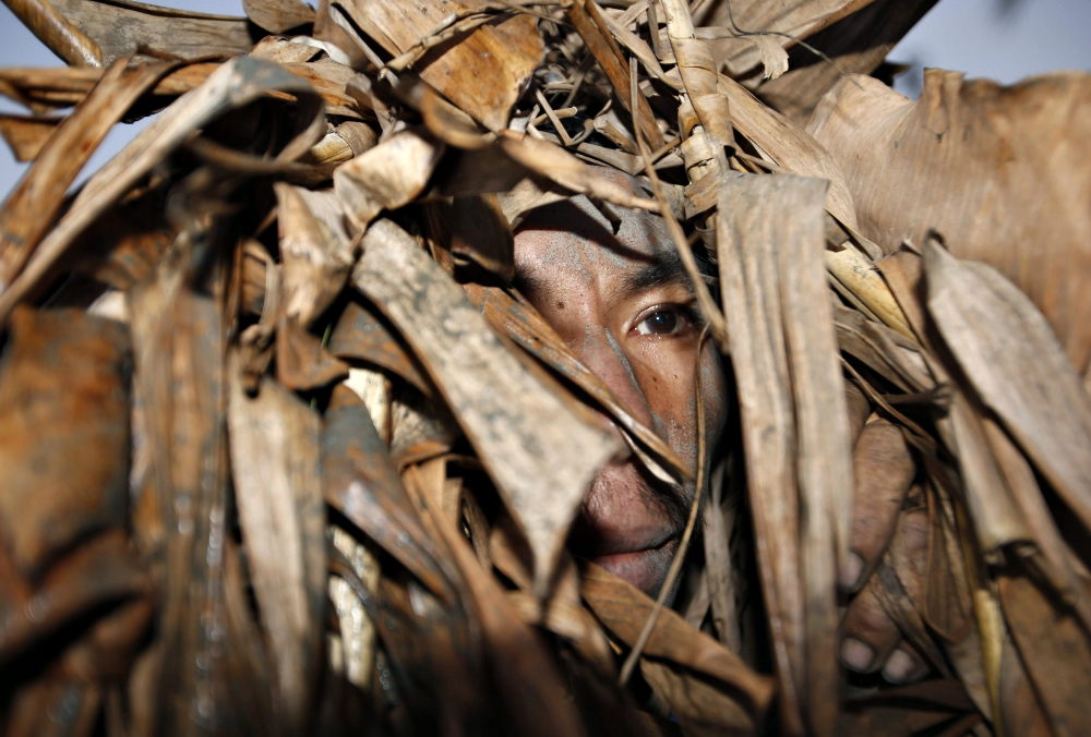 A devotee peeks from banana leaves covering his head as he participates in a religious ritual known locally as "Taong Putik" (Mud People), in the village of Bibiclat, Philippines, while celebrating the feast of St. John the Baptist in June 2014. (CNS)