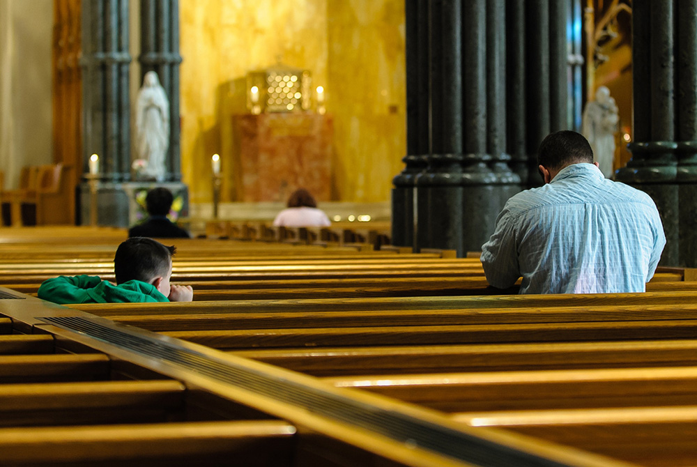 A child watches his father pray inside the Cathedral of Sts. Peter and Paul in Providence, Rhode Island. (CNS/Bob Mullen)
