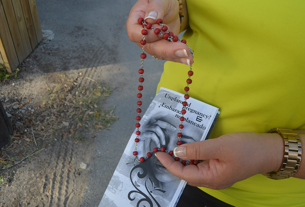 A counselor at the McAllen Pregnancy Center, a Catholic pro-life facility, holds a rosary and literature about abortion during a 2015 walk outside a clinic that provides abortions in McAllen, Texas. (CNS/The Valley Catholic/Rose Ybarra)