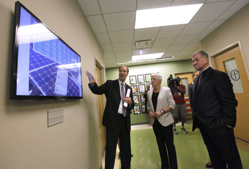 Archbishop Blase J. Cupich of Chicago, right, and Gina McCarthy, administrator of the U.S. Environmental Protection Agency, look over a board with Ted Hudon that displays the solar panel activity at Old St. Mary's School in Chicago July 24, 2015.