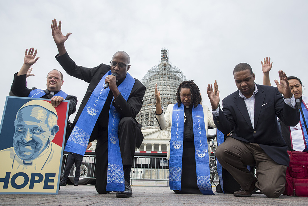 Faith leaders pray as low-wage contract workers from the U.S. Capitol and other federal buildings rally during a strike over wages Sept. 22, 2015, in Washington. (CNS/Joshua Roberts)