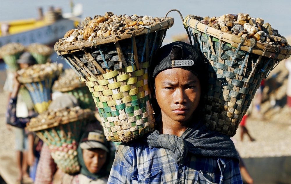 Children in Yangon, Myanmar, carry baskets loaded with gravel used for construction in 2015. (CNS/EPA/Rungroj Yongrit)
