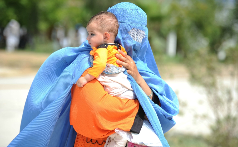 A displaced Afghan woman arrives with her child July 16, 2016, at a U.N. High Commissioner for Refugees camp upon their voluntary return to Afghanistan's Nangarhar Province from neighboring Pakistan. (CNS/Reuters/Ghulamullah Habibi)