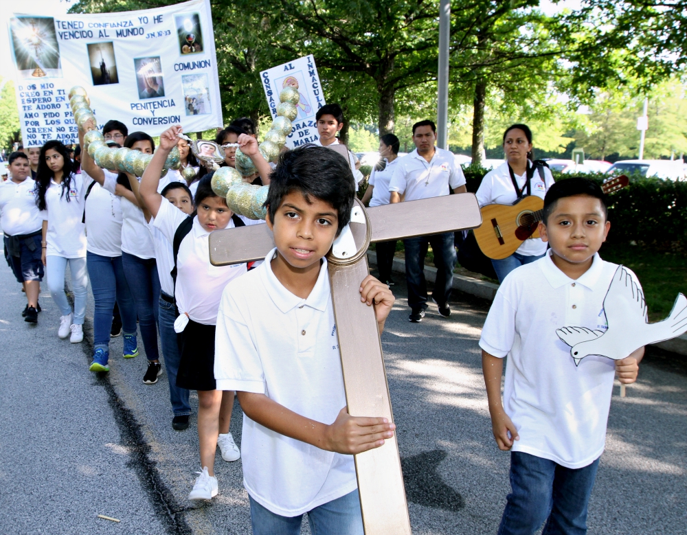 Jesus Solorio, 11, carries a cross during a Eucharistic Congress procession June 17, 2017, in College Park, Ga., in the Atlanta Archdiocese. He is a parishioner of St. Thomas Aquinas Church in Alpharetta, Ga. (CNS/Georgia Bulletin/Michael Alexander)