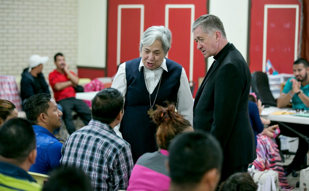 Sr. Norma Pimentel, executive director of Catholic Charities of the Rio Grande Valley, and Chicago Cardinal Blase Cupich greet asylum seekers at the Humanitarian Respite Center at Sacred Heart Church in McAllen, Texas, Aug. 15. (CNS/Courtesy of Catholic E