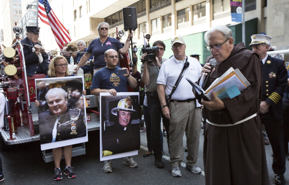 Franciscan Fr. Chris Keenan, chaplain for the New York Fire Department, reads the last homily from Franciscan Fr. Mychal Judge (on poster, center) during the Walk of Remembrance in New York City Sept. 11 this year. (CNS/Octavio Duran)