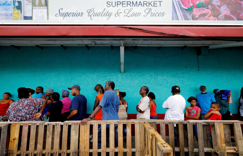 Victims of Hurricane Irma wait behind a makeshift barricade for admission to a local supermarket shortly after curfew was lifted in St. Thomas in the U.S. Virgin Islands. (CNS/Reuters/Jonathan Drake)