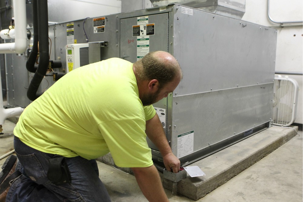 Technician Brian Wayson of AirStream Mechanical in Cincinnati checks wiring on a high-efficiency air conditioning unit at St. John Fisher Church in Newtown, Ohio, Aug. 17, 2017. (CNS)