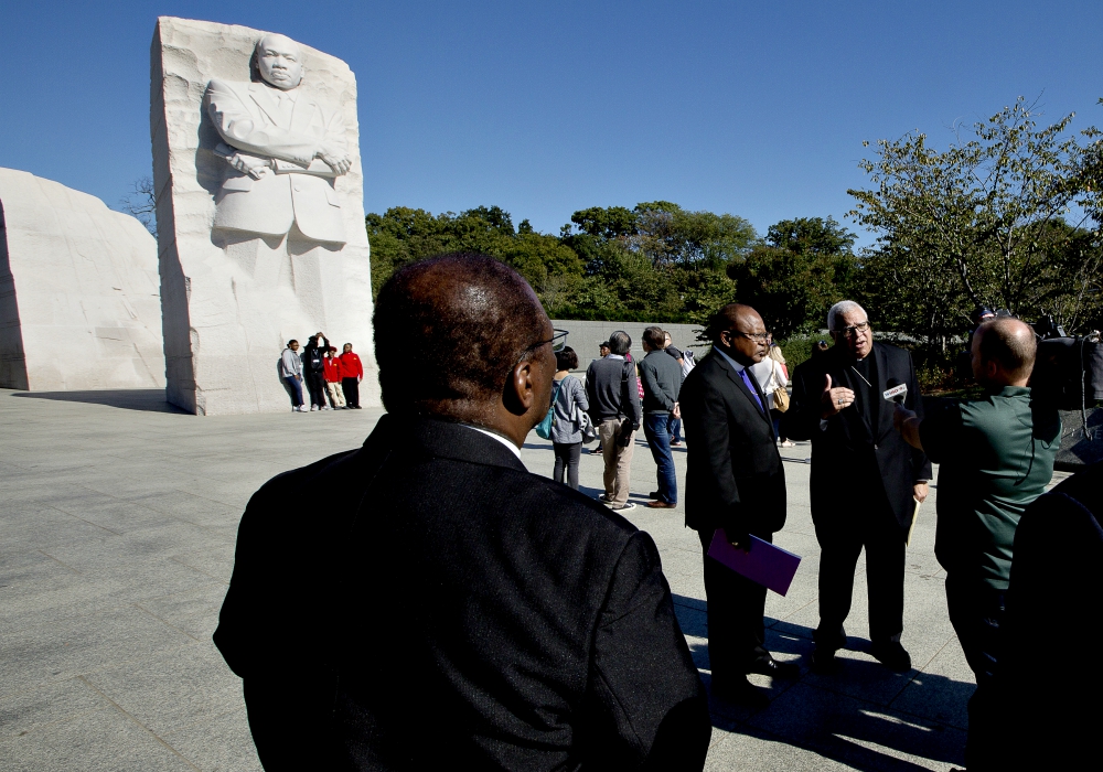 Bishop George Murry (facing camera, right), chair of the U.S. bishops' Ad Hoc Committee Against Racism, conducts an interview near the Martin Luther King Jr. Memorial in Washington Oct. 2. (CNS/Tyler Orsburn)