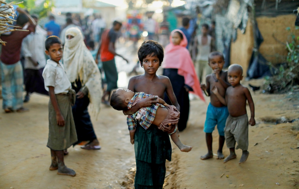 A young Rohingya refugee carries a child Oct. 10 while walking in a camp near Cox's Bazar, Bangladesh. (CNS/Reuters/Damir Sagolj)