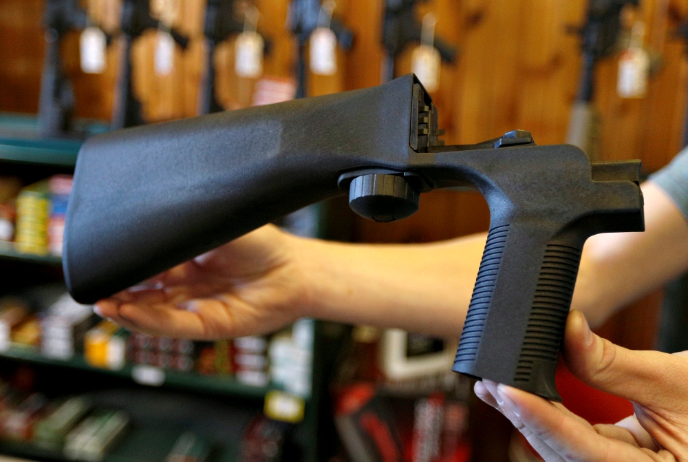 An employee at a gun shop in Orem, Utah, is seen in October 2017 holding a bump stock that attaches to a semiautomatic rifle to increase the firing rate. (CNS/Reuters/George Frey)