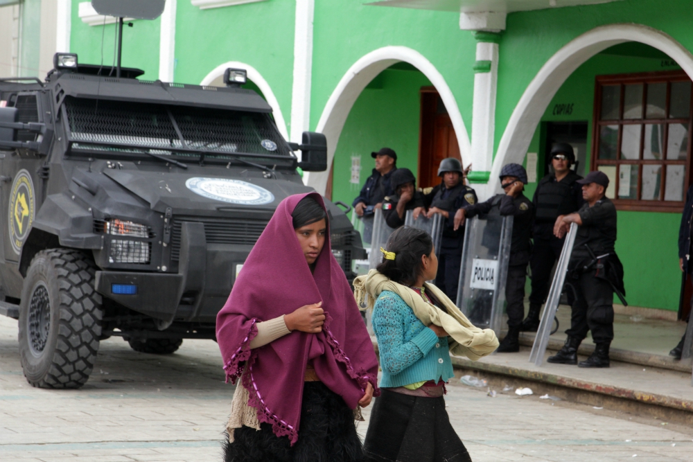 Indigenous women pass riot police standing guard on the city square of San Juan Chamula, Mexico, in late July. (CNS/EPA/Rene Arauxo) 