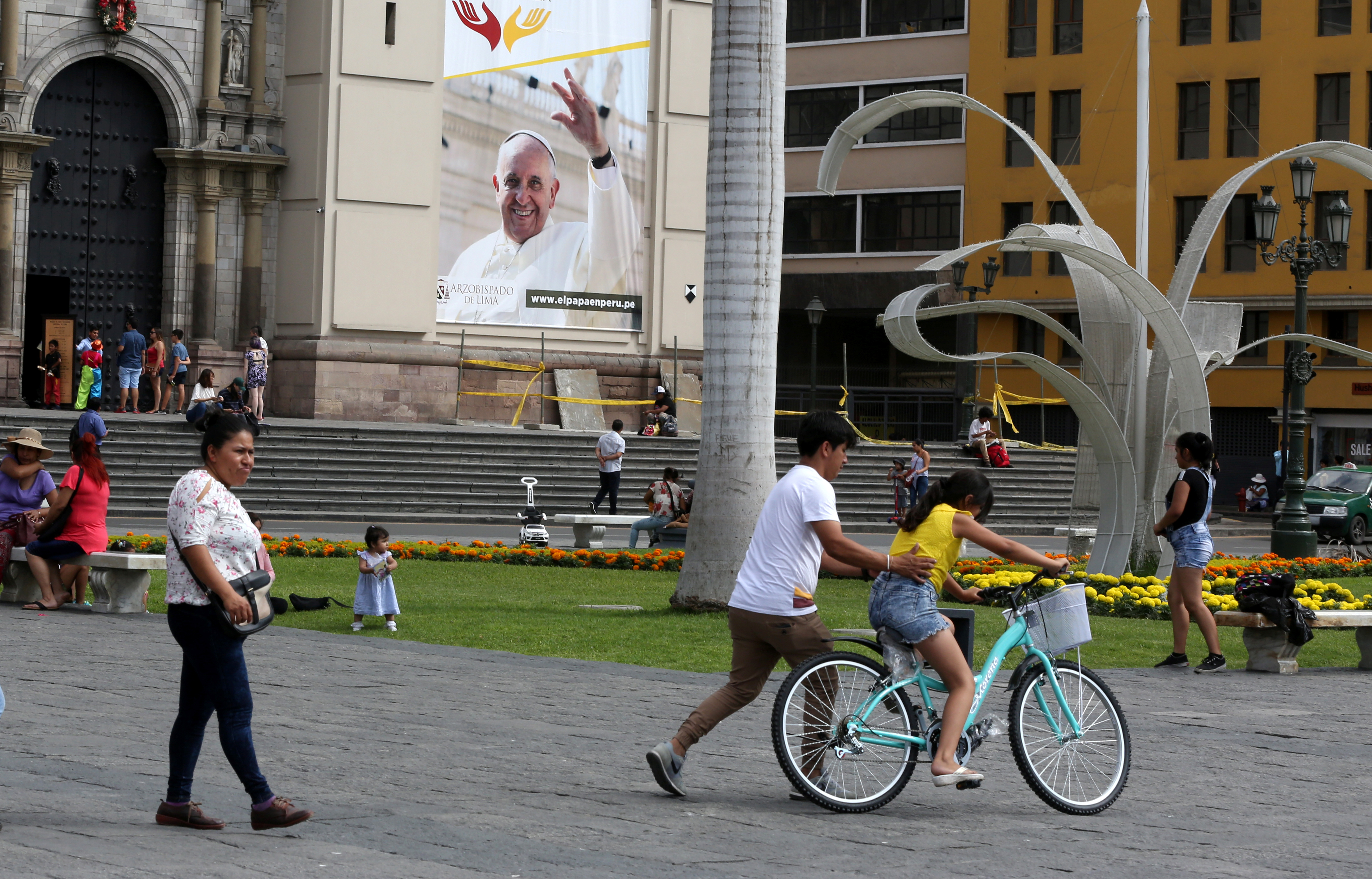 People walk near a banner with an image of Pope Francis on the facade of the cathedral in Lima, Peru, Jan. 3. On Jan. 15, Francis will begin a six-day visit to Chile and Peru. (CNS/Reuters/Mariana Bazo)