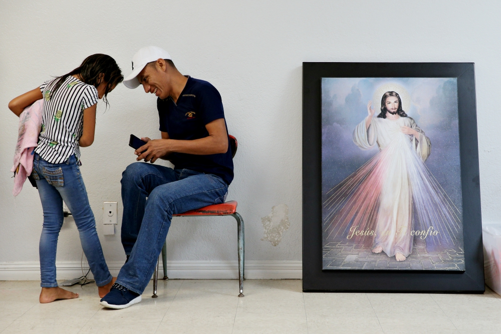 A Guatemalan immigrant and his daughter, recently released from detention through the U.S. immigration policy called "catch and release," talk with each other April 14 at the Catholic Charities relief center in McAllen, Texas. (CNS/Reuters/Loren Elliott)
