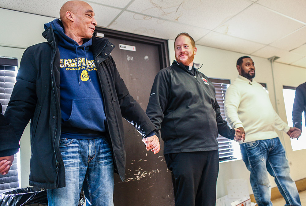 Fr. Matt O'Donnell, pastor of St. Columbanus Parish in Chicago, prays with volunteers before they open the church's Wednesday food pantry in a file photo. In 2020, the church received an estimated $70,000 in Paycheck Protection Program loans. (CNS)