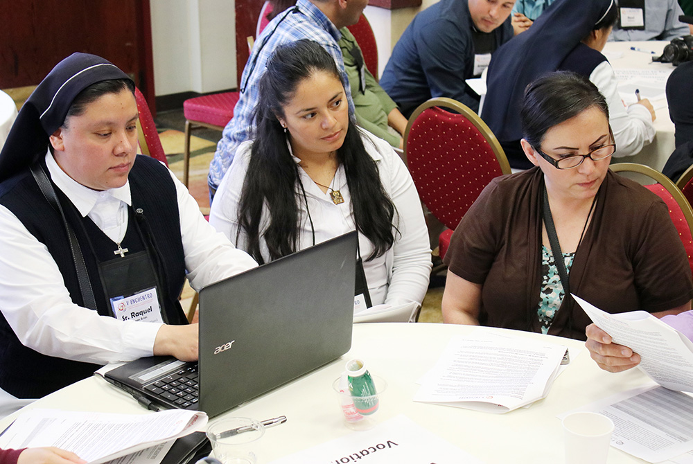 Sr. Raquel De Leon types notes as Victoria Rodriguez of the Diocese of Boise, Idaho, and Maria Elena Ruiz of the Archdiocese of Portland, Oregon, listen to speakers June 22, 2018, at the Region XII gathering of V Encuentro in Portland, Oregon. (CNS)