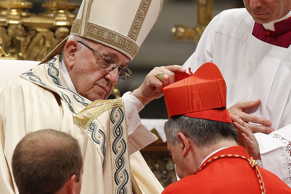 In St. Peter's Basilica at the Vatican in 2018, Pope Francis place a red biretta on Cardinal Giovanni Angelo Becciu, then Vatican substitute secretary of state, during a consistory at which Becciu and 13 others became cardinals. (CNS/Paul Haring)