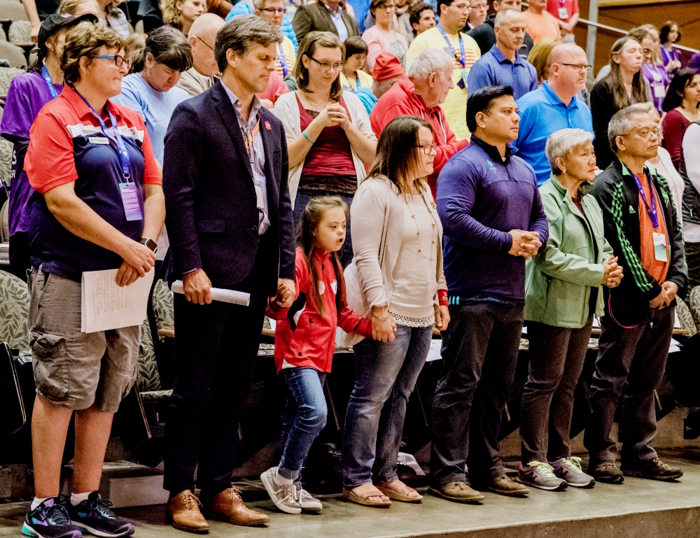 Tim Shriver, second from left, holds hands with Frannie Ronan, 9, during a June 30 Mass on the campus of the University of Washington in Seattle for athletes at the Special Olympics. (CNS/Courtesy of Seattle Archdiocese/Katie Niemar Photography)