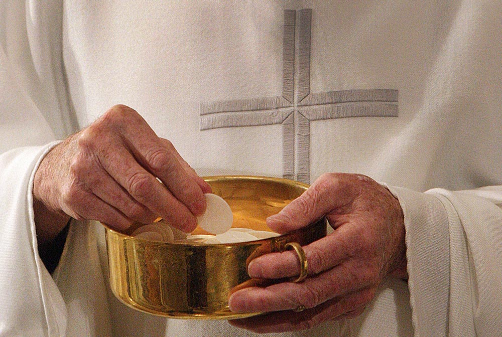 A priest prepares to distribute Communion during Mass in Washington. (CNS/Bob Roller)