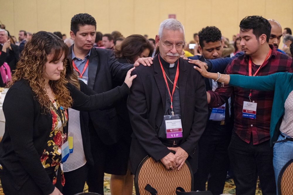 Young Catholic adults pray over Bishop Anthony Taylor of Little Rock, Arkansas, Sept. 21 during an evening encounter between young adults and their bishops at the V Encuentro in Grapevine, Texas. (CNS/Texas Catholic Herald/James Ramos)