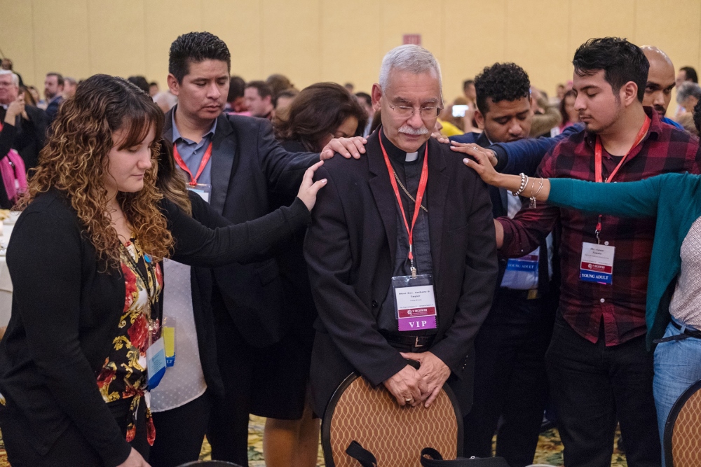 Young Catholic adults pray over Bishop Anthony Taylor of Little Rock, Arkansas, Sept. 21 during an evening encounter between young adults and their bishops at the V Encuentro in Grapevine, Texas. (CNS/Texas Catholic Herald/James Ramos) Young Catholic adults pray over Bishop Anthony Taylor of Little Rock, Arkansas, Sept. 21 during an evening encounter between young adults and their bishops at the V Encuentro in Grapevine, Texas. (CNS/Texas Catholic Herald/James Ramos)