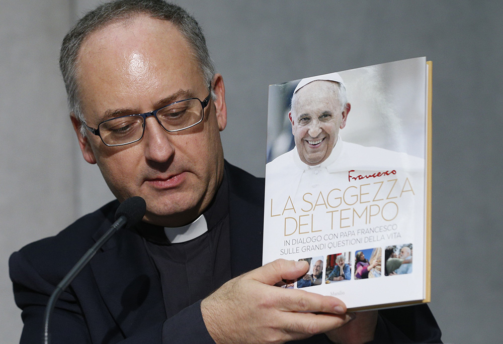 Jesuit Fr. Antonio Spadaro holds a copy of the book "Sharing the Wisdom of Time" during a briefing Oct. 23, 2018, at the Vatican. (CNS/Paul Haring)