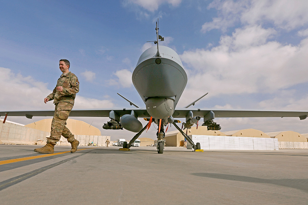 A U.S. service member passes in front of an MQ-9 Reaper drone at the Kandahar air base in Afghanistan. (CNS/Reuters/Omar Sobhani)