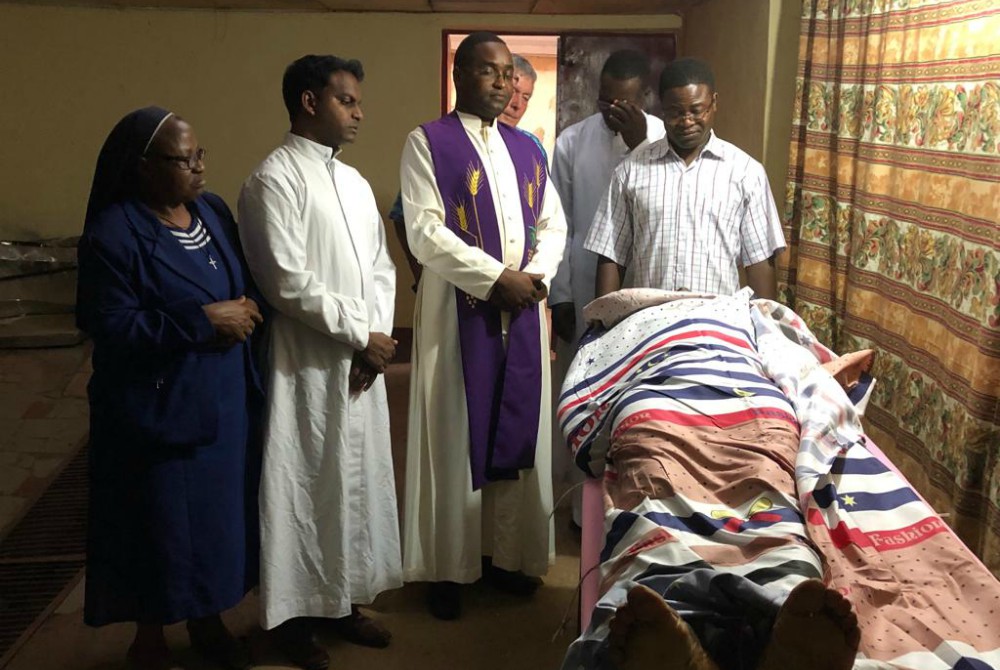 Fr. Richard Njoroge, in purple stole, and others pray over the body of Kenyan Mill Hill Fr. Cosmas Omboto Ondari, parochial vicar of St. Martin of Tours Parish in Kembong, Cameroon, who was killed Nov. 21, 2018, outside his church. (CNS)
