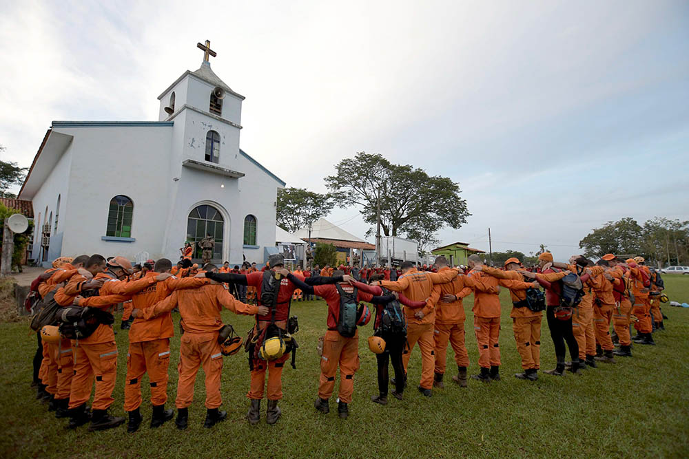 Members of a rescue team pray before working in a collapsed tailings dam owned by mining company in Brumadinho, Brazil, Feb. 13, 2019. (CNS/Reuters/Washington Alves)