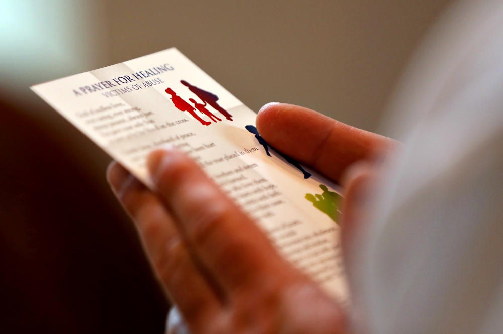 A clergyman reads a prayer card during a Mass with special intentions for survivors of abuse and for abuse prevention in the chapel of the headquarters of the U.S. Conference of Catholic Bishops in Washington April 8. (CNS/Bob Roller)