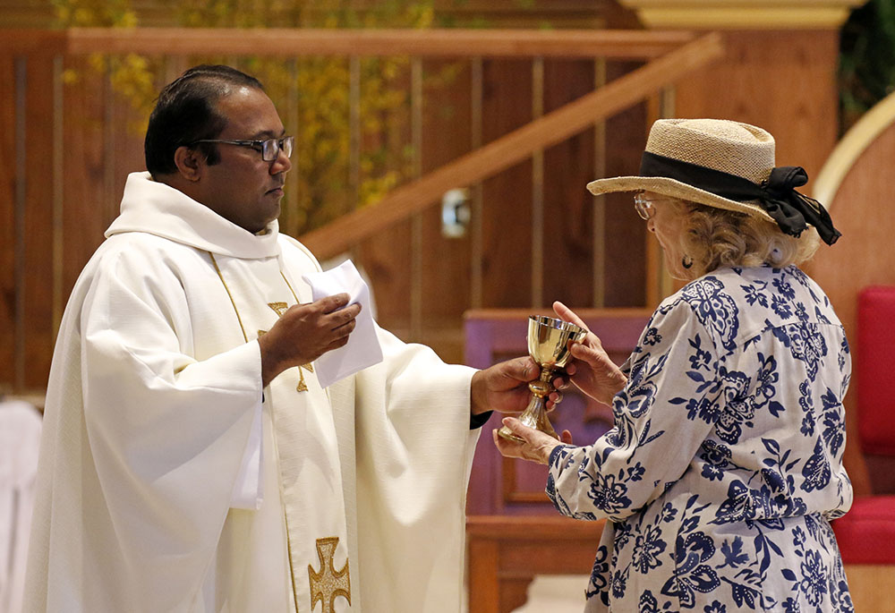 Fr. Chinthaka Perera gives the Communion cup to a woman during Mass at St. Boniface Martyr Church in Sea Cliff, New York, April 25, 2019. (CNS/Gregory A. Shemitz)