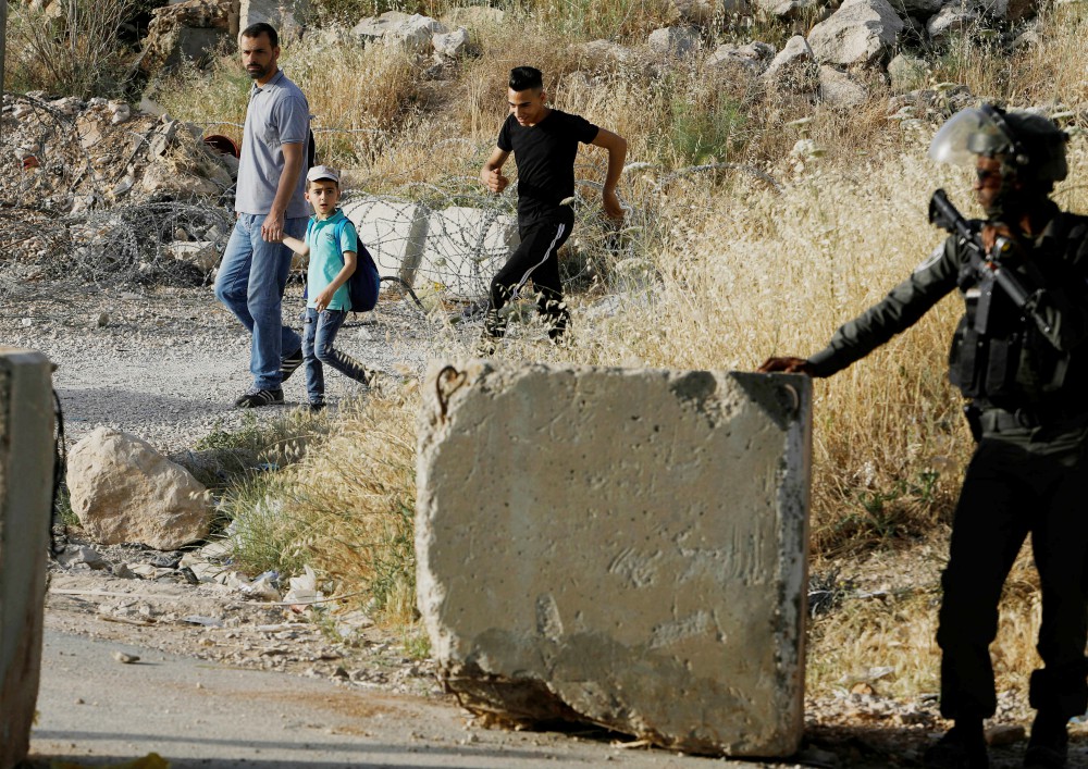 An Israeli border policeman stands guard not far from Ramallah, West Bank, May 17, 2019, as Palestinians make their way to attend Friday prayer at al-Aqsa mosque in Jerusalem's Old City. (CNS/Reuters/Raneen Sawafts)