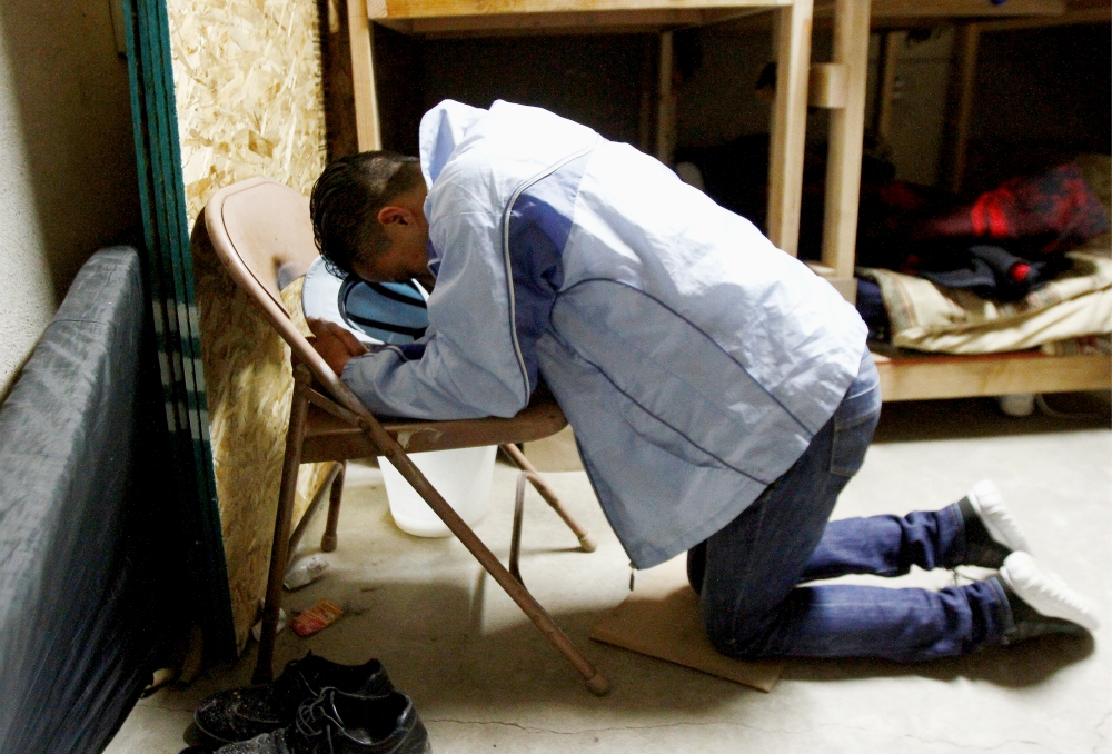A Honduran migrant prays at a shelter in Tijuana, Mexico, March 19 while awaiting legal proceedings for his asylum case. (CNS/Reuters/Jorge Duenes)