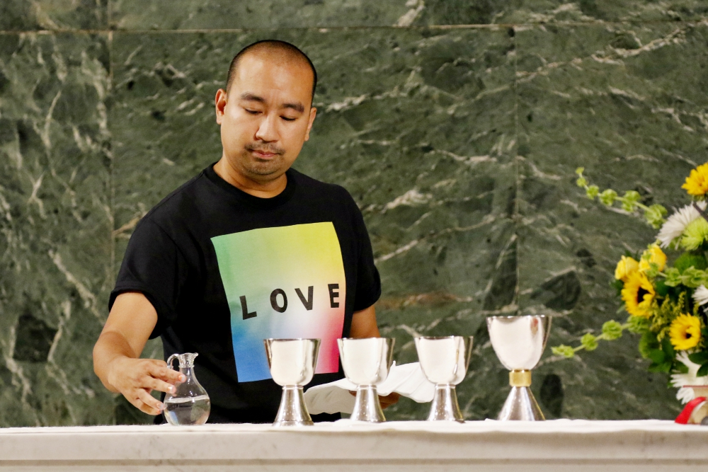 Altar server Angelo Alcasabas prepares the altar during an annual "Pre-Pride Festive Mass" at St. Francis of Assisi Church in New York City June 29. Jesuit Fr. James Martin presided at the liturgy, which is hosted by the parish's LGBT outreach ministry.