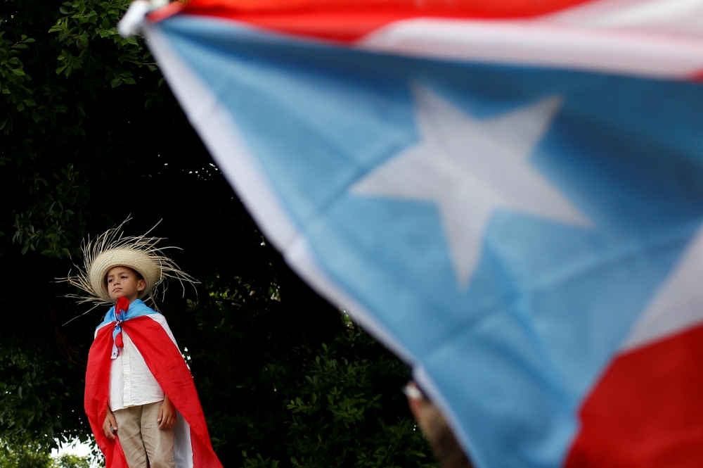 A youth draped in a Puerto Rican flag attends a rally to celebrate the resignation of Puerto Rican Gov. Ricardo Rosselló in San Juan July 25. (CNS/Reuters/Marco Bello)