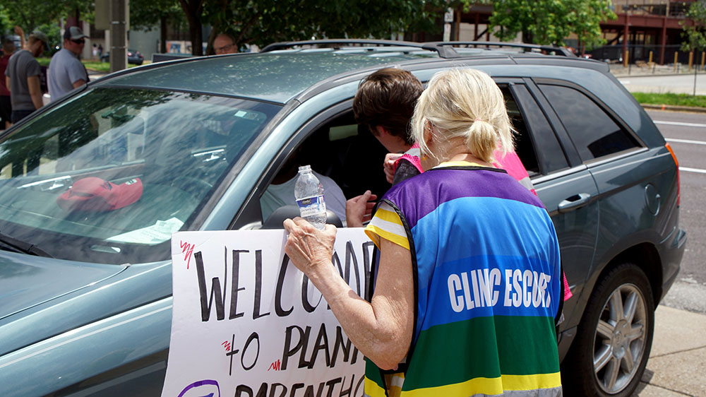 A Planned Parenthood escort advises a pro-life advocate to not stop cars coming into the organization's facility in St. Louis June 4, 2019.