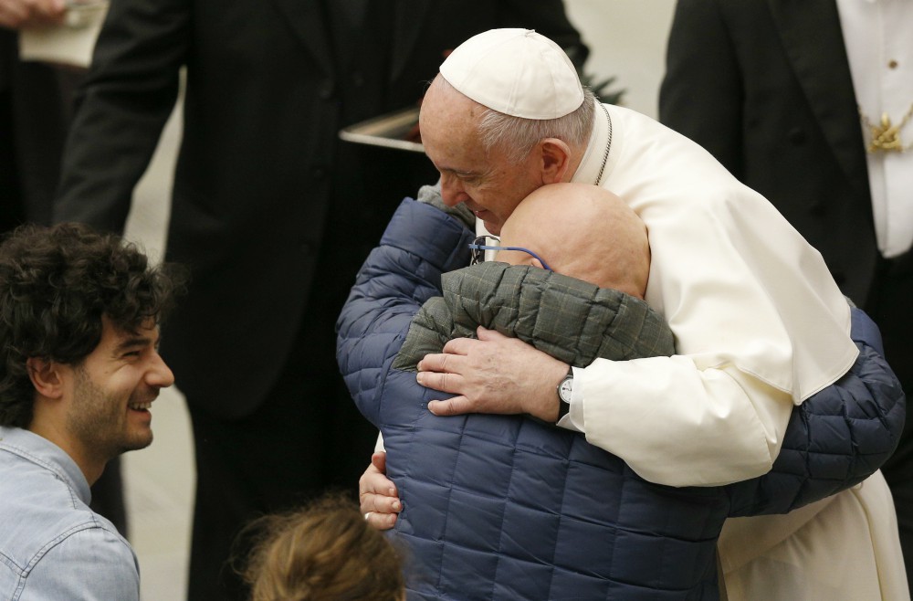 Pope Francis embraces a man as he meets disabled people during his general audience in Paul VI hall at the Vatican Jan. 8. (CNS/Paul Haring)