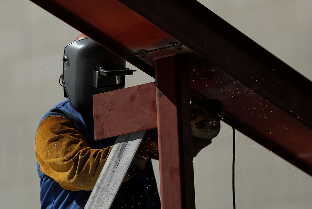 A construction worker uses a grinder on a metal beam at a construction site Aug. 10, 2017, in Los Angeles. (CNS/Reuters/Mike Blake)