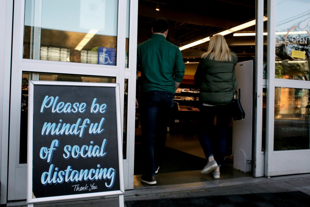 Shoppers enter a Seattle grocery store March 17 near a sign requesting social distancing, following reports of coronavirus cases in the area. (CNS/Reuters/David Ryder) Shoppers enter a Seattle grocery store March 17 near a sign requesting social distancing, following reports of coronavirus cases in the area. (CNS/Reuters/David Ryder)