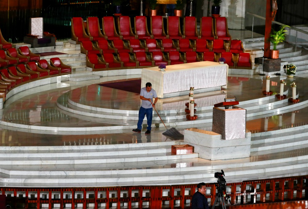A worker cleans the floor before Cardinal Carlos Aguiar Retes of Mexico City celebrates an online Mass via YouTube and television at the Basilica of Our Lady of Guadalupe in Mexico City March 22. (CNS/Reuters/Henry Romero)
