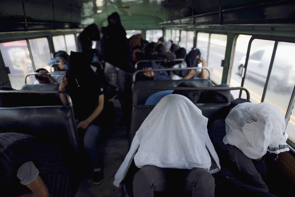 Guatemalan migrants cover themselves while on a bus outside La Aurora International Airport in Guatemala City March 19 after being deported from the U.S. (CNS/Reuters/Fabricio Alonso)