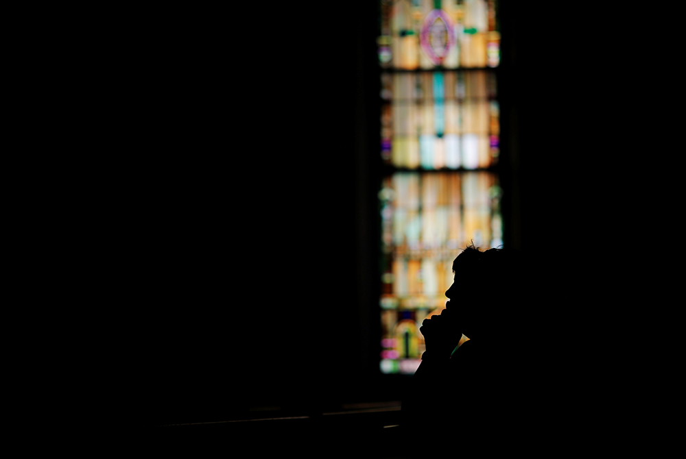 A woman prays inside a Catholic church in this 2017 file photo. (CNS/Reuters/Brian Snyder)