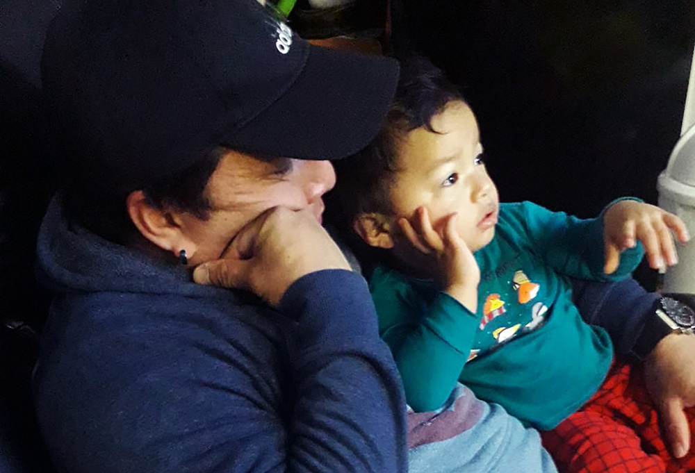 Juan Vasquez, a grocery store worker in Uniondale, New York, cuddles with his toddler Robert while watching TV at home March 28, 2020. (CNS/Courtesy of Tanya Granillo de Vasquez)