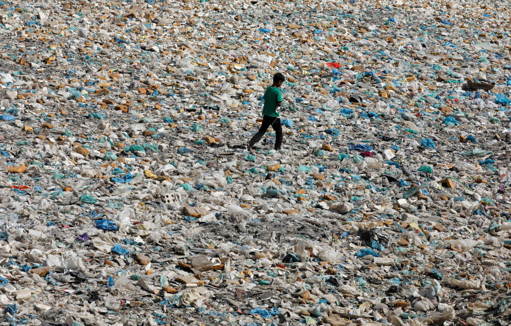 A boy walks over a drainage channel littered with garbage in Karachi, Pakistan, on Earth Day April 22, 2020. (CNS photo/Akhtar Soomro, Reuters)