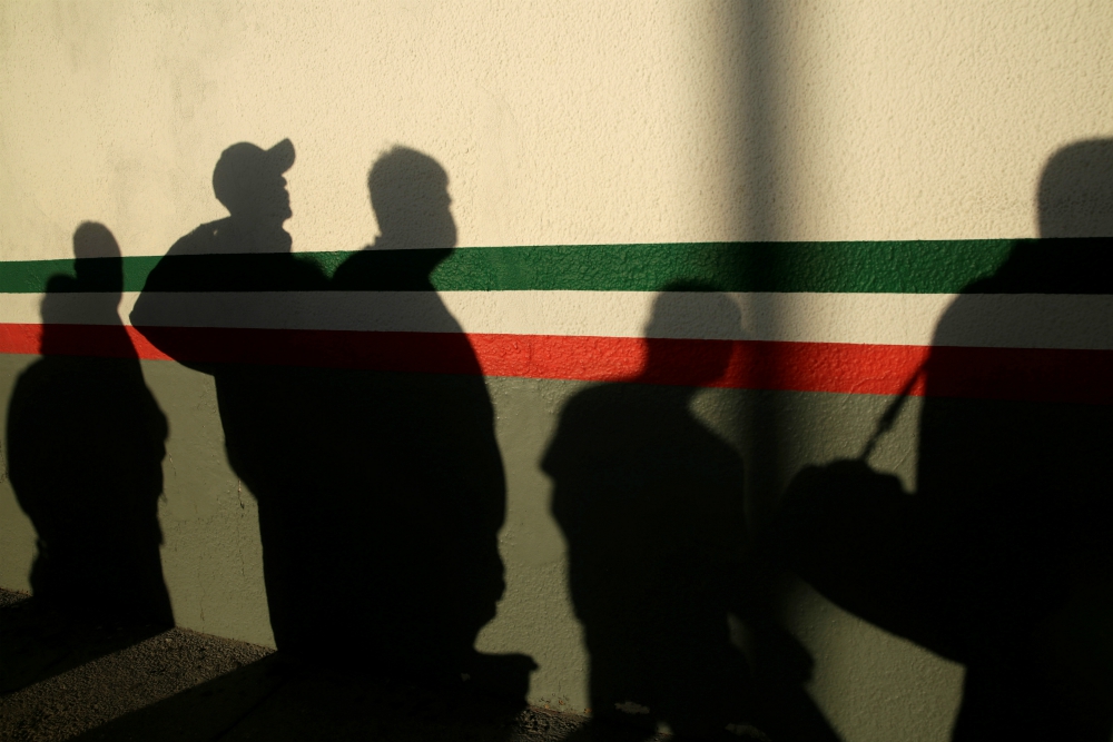 Immigrants in Ciudad Juárez, Mexico, cast shadows on a National Institute of Migration building after they were deported from the United States April 21 during the coronavirus pandemic. (CNS/Reuters/Jose Luis Gonzalez)