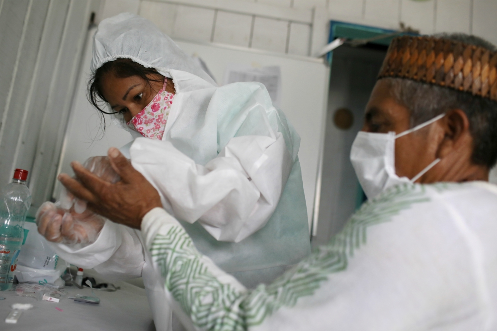 Neurilene Cruz, a Kambeba indigenous nurse technician, conducts a COVID-19 test on Waldemir da Silva, 61, a Kambeba indigenous chief, in Tres Unidos, Brazil, May 21. (CNS/Reuters/Bruno Kelly)