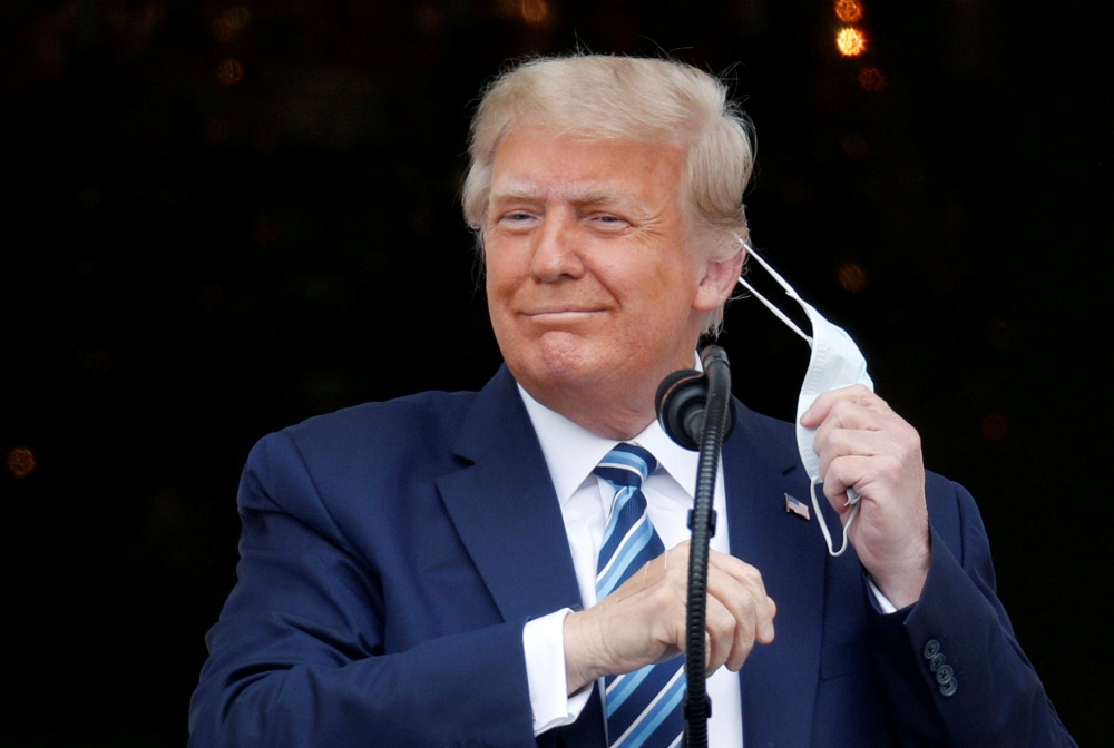 President Donald Trump takes off his face mask Oct. 10 as he comes out on a White House balcony in Washington to speak to supporters gathered for a rally on the South Lawn. (CNS/Reuters/Tom Brenner) President Donald Trump takes off his face mask Oct. 10 as he comes out on a White House balcony in Washington to speak to supporters gathered for a rally on the South Lawn. (CNS/Reuters/Tom Brenner)
