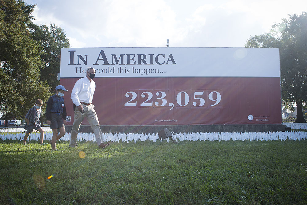 People in Washington walk near a temporary memorial for the victims of COVID-19 Oct. 23. Each day the artist adds new flags and changes the numbers to the installation as the death toll rises. As of Nov. 17, over 246,800 Americans had died from the diseas